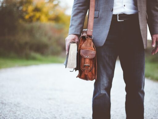 man holding book on road during daytime