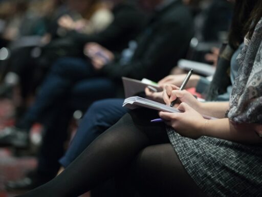 selective focus photography of people sitting on chairs while writing on notebooks